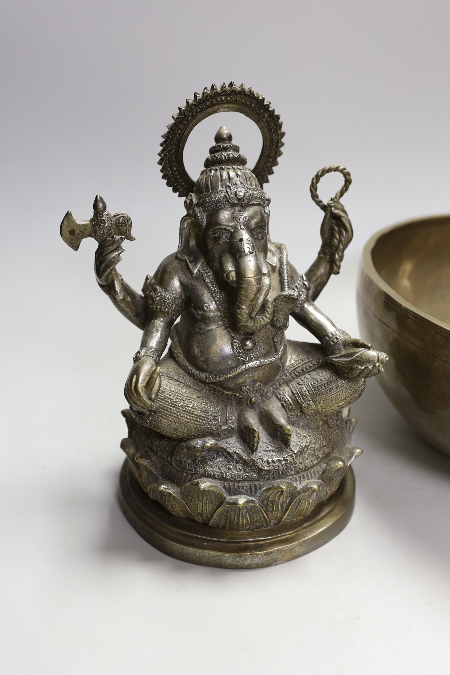 A plated figure of Ganesha and a Tibetan singing bowl with striker